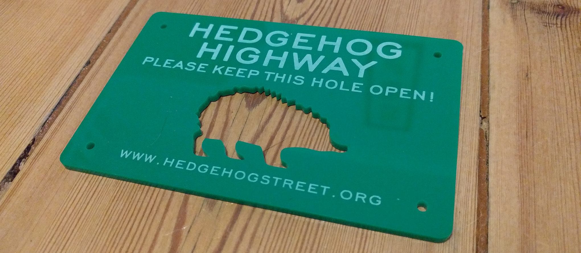 A hedgehog sign asking not to cover up the hole in the fence